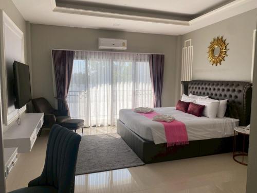 a bedroom with a large bed and a room with a television at พาราไดซ์รีสอร์ต สังขละบุรี Paradise Resort at Sangkhlaburi in Sangkhla Buri