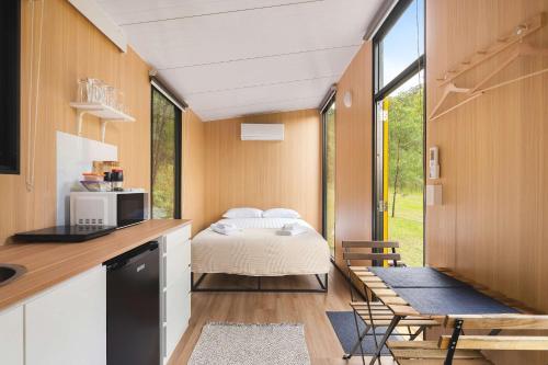 a room with a bed and a kitchen with a window at Wombat Hideaway by Tiny Away in Laguna