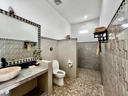 ein Badezimmer mit Waschbecken, Toilette und Spiegel in der Unterkunft Mejore Beach Hotel in Amed