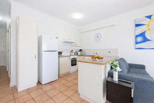 a kitchen and living room with a white refrigerator at The Anchorage Escape Apartment - Steps away from City, Ferry and Stadium Townsville in Townsville