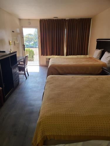 a hotel room with two beds and a desk at Relax Inn And Suites in El Cajon
