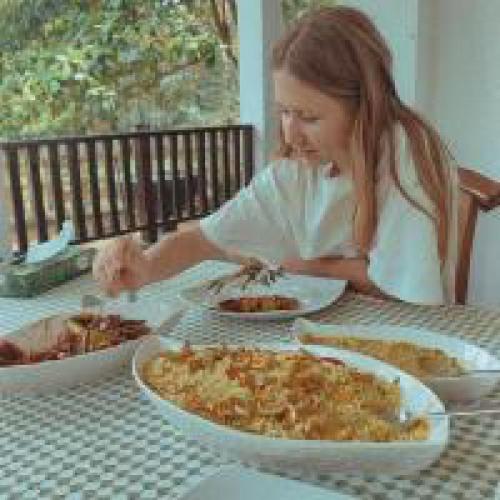 a woman sitting at a table with plates of food at Moonlit serenity Tangalle in Tangalle