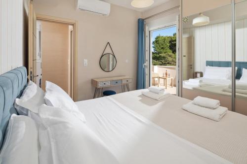 a bedroom with two white beds and a tub at Klio by Vintage Travel in Agios Georgios