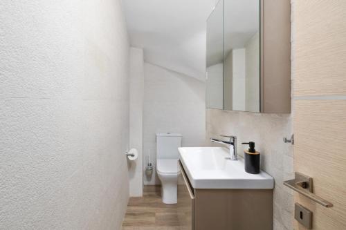 a bathroom with a sink and a toilet and a mirror at Klio by Vintage Travel in Agios Georgios