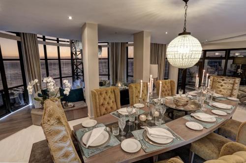 comedor con mesa, sillas y lámpara de araña en Ocean View Penthouse en Strand