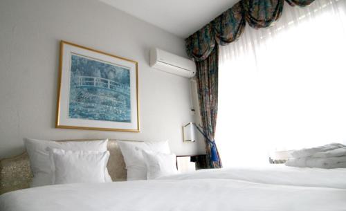 a bedroom with two white beds and a window at Hotel Königshof The Arthouse in Cologne
