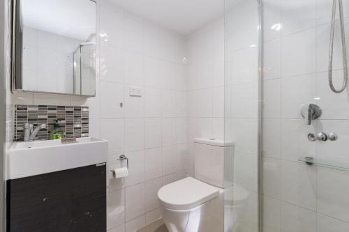 a white bathroom with a toilet and a shower at Manly Beach Guesthouse in Sydney