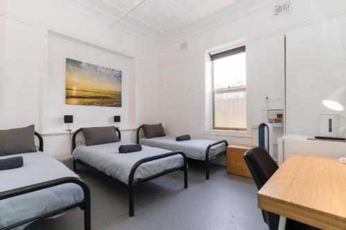 a room with three beds and a table at Manly Beach Guesthouse in Sydney