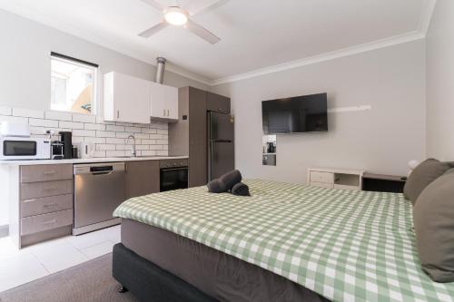 a bedroom with a bed with a green and white checkered blanket at Manly Beach Guesthouse in Sydney