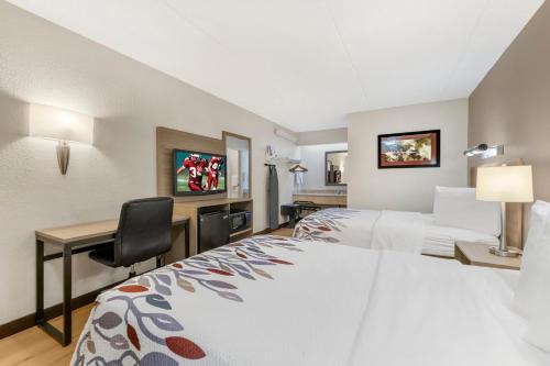 a hotel room with two beds and a desk at Red Roof Inn Buffalo - Niagara Airport in Williamsville