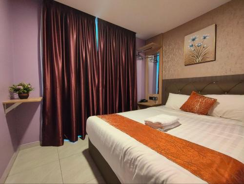 a bedroom with a large bed with red curtains at Hotel Mawar Inn in Jenjarum