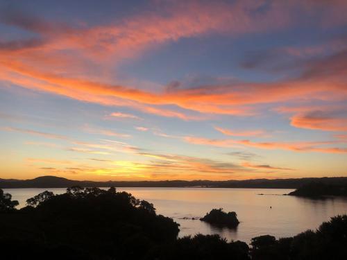 a sunset over a large body of water at W91 Stylish, Modern, Beach view in Tutukaka