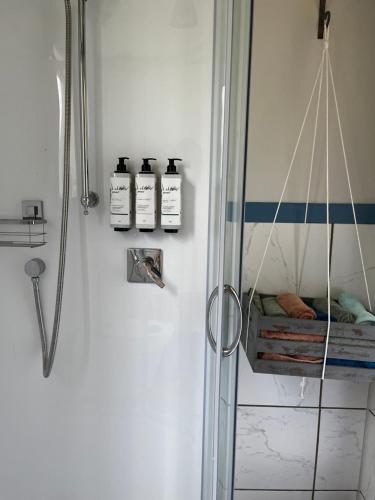 a bathroom with three bottles of soap and a shower at Wisteria Way in Opononi
