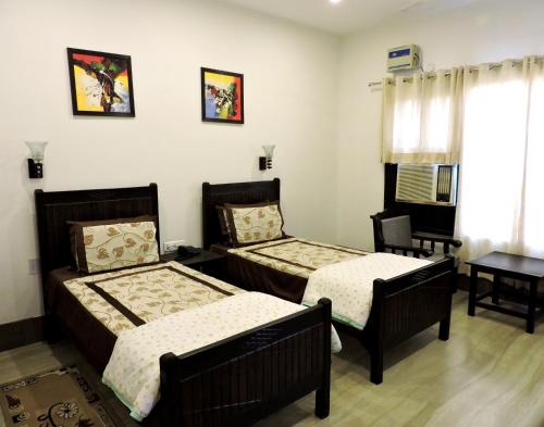 a bedroom with two beds and a table and a window at Pearl of Taj Home Stay in Agra