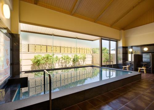 a swimming pool in a house with a large window at ウェルネスハウスさらい in Nomi