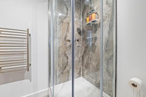 a shower with a glass door in a bathroom at Pleasant and snuggly modern 2-floored town centre apartment in Hull
