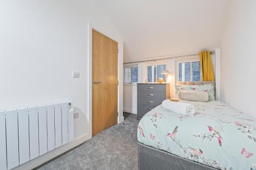 a bedroom with a bed and a dresser and windows at Pleasant and snuggly modern 2-floored town centre apartment in Hull