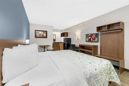 a bedroom with a large white bed and a desk at HomeTowne Studios by Red Roof Buffalo - Niagara Airport in Williamsville