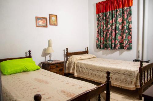 a bedroom with two beds and a window with a curtain at Hotel Barcelona in General Alvear