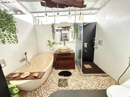 a bathroom with a tub and a shower and a sink at Homestay Aesthetic Jogja in Gondowulung