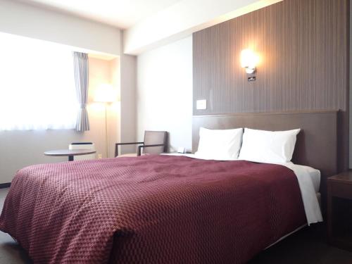 a hotel room with a bed with a red blanket at Castle Inn Toyokawa in Toyokawa