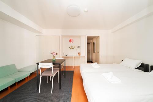 a room with two beds and a table and a couch at Kamata Opus2 Apartment in Tokyo