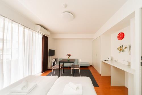 a white room with a table and a bed at Kamata Opus2 Apartment in Tokyo