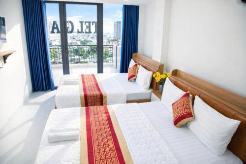 two beds in a room with a large window at Gia Bảo Hotel Thủ Đức in Ho Chi Minh City