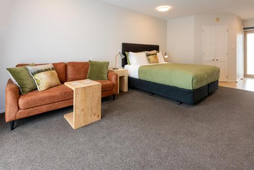 a bedroom with a bed and a couch and a bed and a table at Tussock Peak Lodge in Hanmer Springs