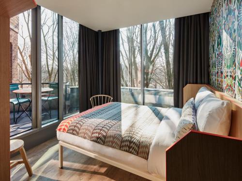 a bedroom with a bed and a large window at Generator Amsterdam in Amsterdam