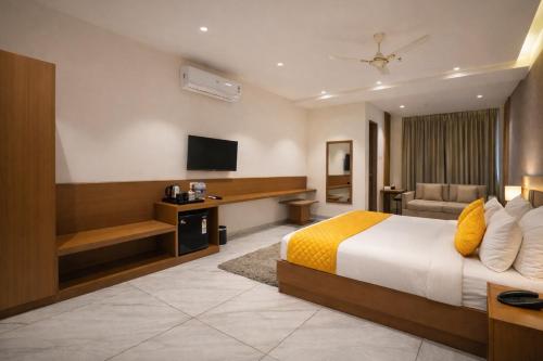 a hotel room with a bed and a television at Solasta Stays and Banquet - Wakad in Pune