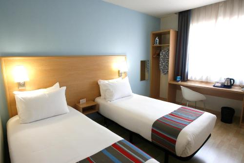 um quarto de hotel com duas camas e uma secretária em Travelodge Torrelaguna em Madri