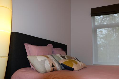 スパにあるUn Air de Châteauのピンクと白の枕が備わるベッド、窓が付いています。