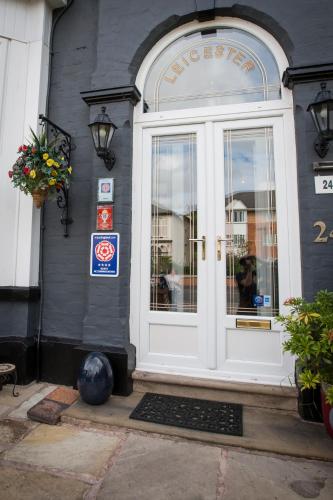 a white door to a store with a sign on it at The Leicester in Southport