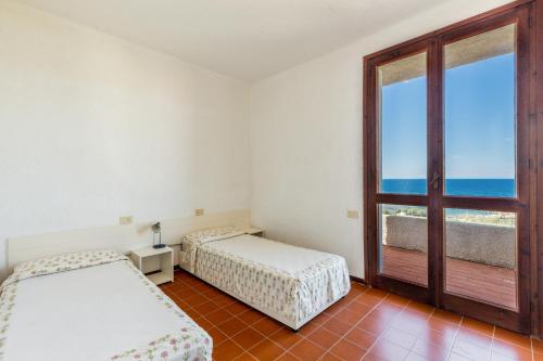 una camera con due letti e una finestra con vista sull'oceano di Residence Baia Santa Reparata a Santa Teresa di Gallura