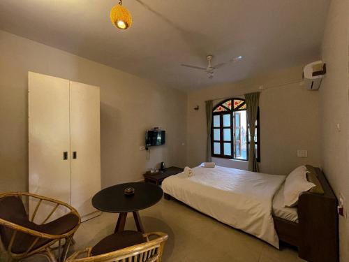 a bedroom with a bed and a table and a window at Casa Aqua Mandrem in Mandrem