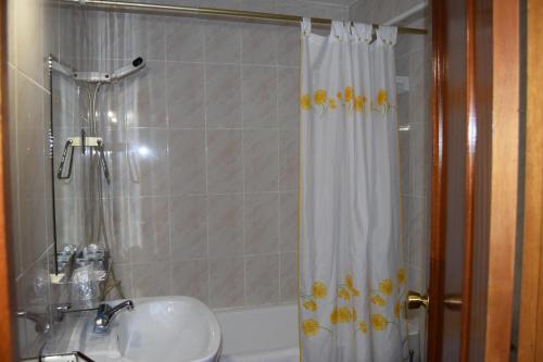 y baño con lavabo y ducha con cortina de ducha. en Hotel Rural Marcos, en Rascafría
