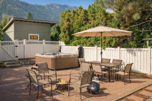 a patio with a table and an umbrella and a hot tub at All Seasons Getaway in Leavenworth