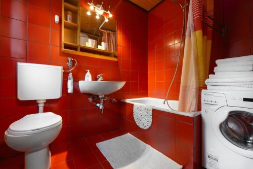 a red bathroom with a toilet and a washing machine at Hugo's House in Rakitna