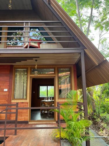 a house with a wooden porch with a deck at Jungle flare in Hampāpura