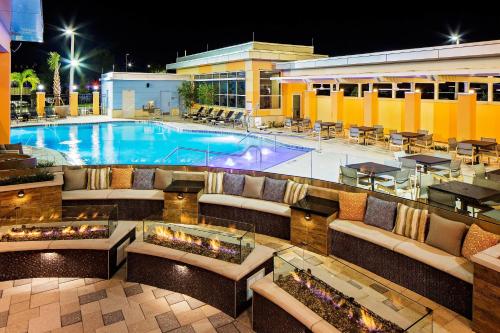 a swimming pool with couches and tables and a hotel at Hyatt House across from Universal Orlando Resort in Orlando