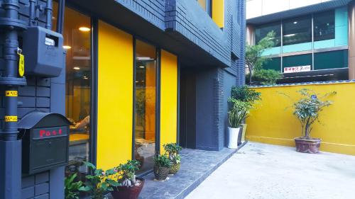 un edificio giallo con piante in vaso di fronte ad esso di Seri Inn Guesthouse a Busan