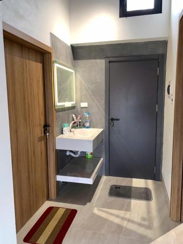 a bathroom with a white sink and a black door at The Little Home in Xuân Dục
