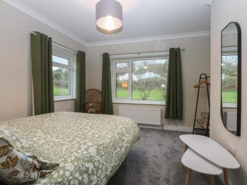 a bedroom with a bed and two windows at Caledfryn in Benllech