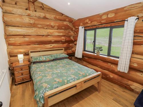 a bedroom with a bed in a log cabin at Douglas Cabin at Salford Court Farm Fishing Cabins in Worcester
