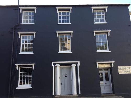 a black house with white doors and windows at Book Heaven in Bridport