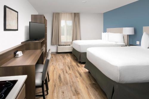 a hotel room with two beds and a desk at Woodspring Suites Orlando International Drive in Orlando