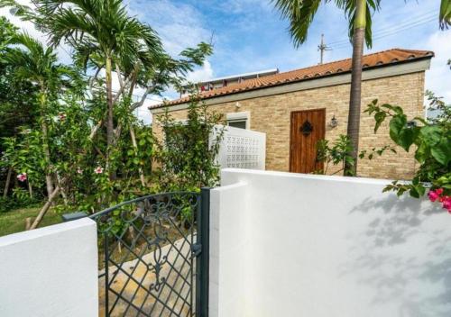 a gate in front of a house with palm trees at Miyakojima Villa Charles in Miyako-jima
