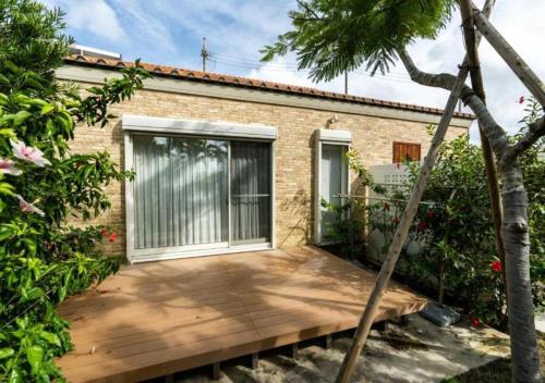 a wooden deck in front of a brick house at Miyakojima Villa Charles in Miyako-jima