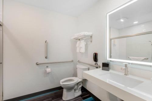 a bathroom with a toilet and a sink and a mirror at Clarion Pointe Prescott Valley in Prescott Valley